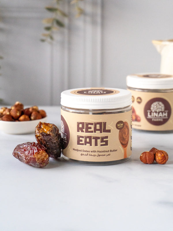 A jar of Hazelnut Butter Stuffed Medjool Dates alongside two plump dates filled with creamy hazelnut butter, highlighting their rich texture and natural goodness.