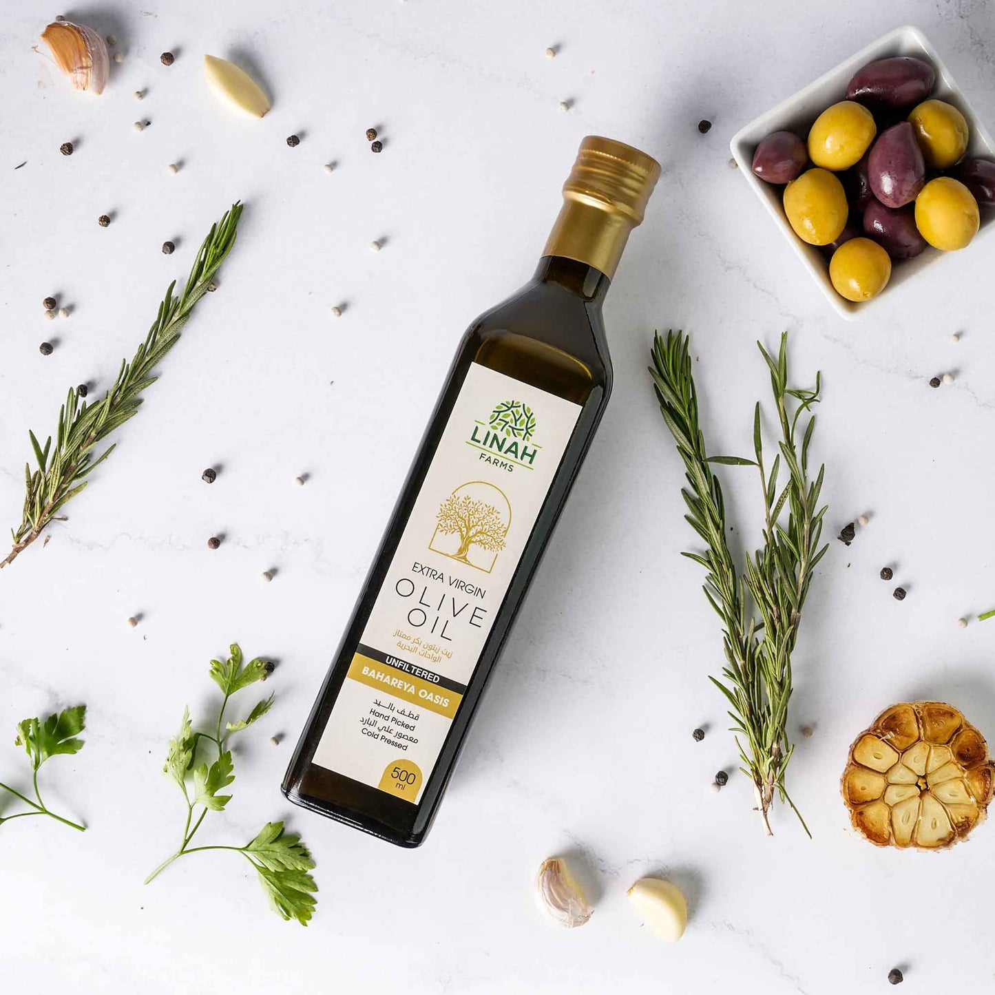 Unfiltered extra-virgin olive oil bottle from Linah Farms lying amid various cooking ingredients 